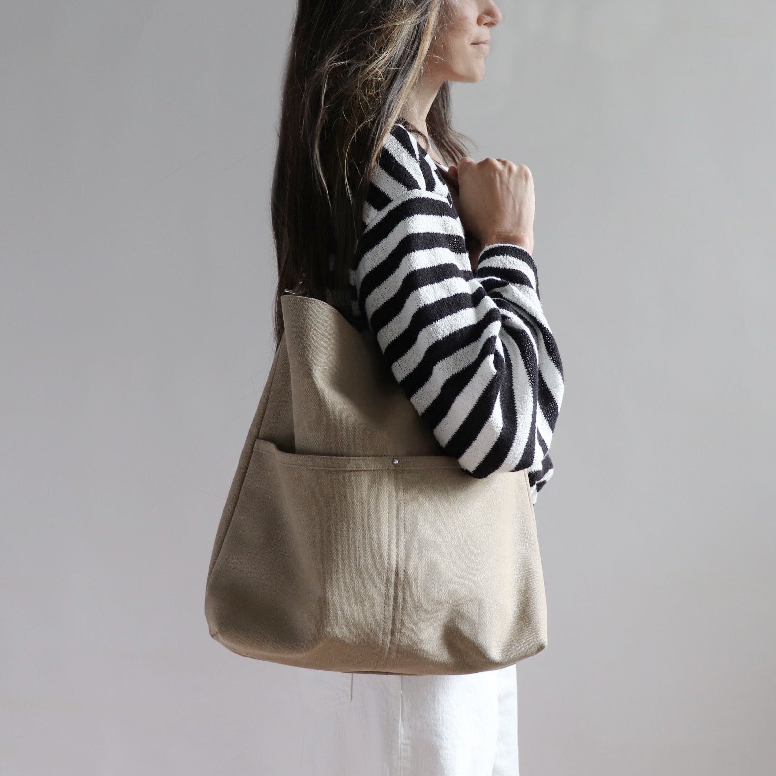 Hobo Style Shoulder Bag in beige canvas shown on model in casual summer outfit