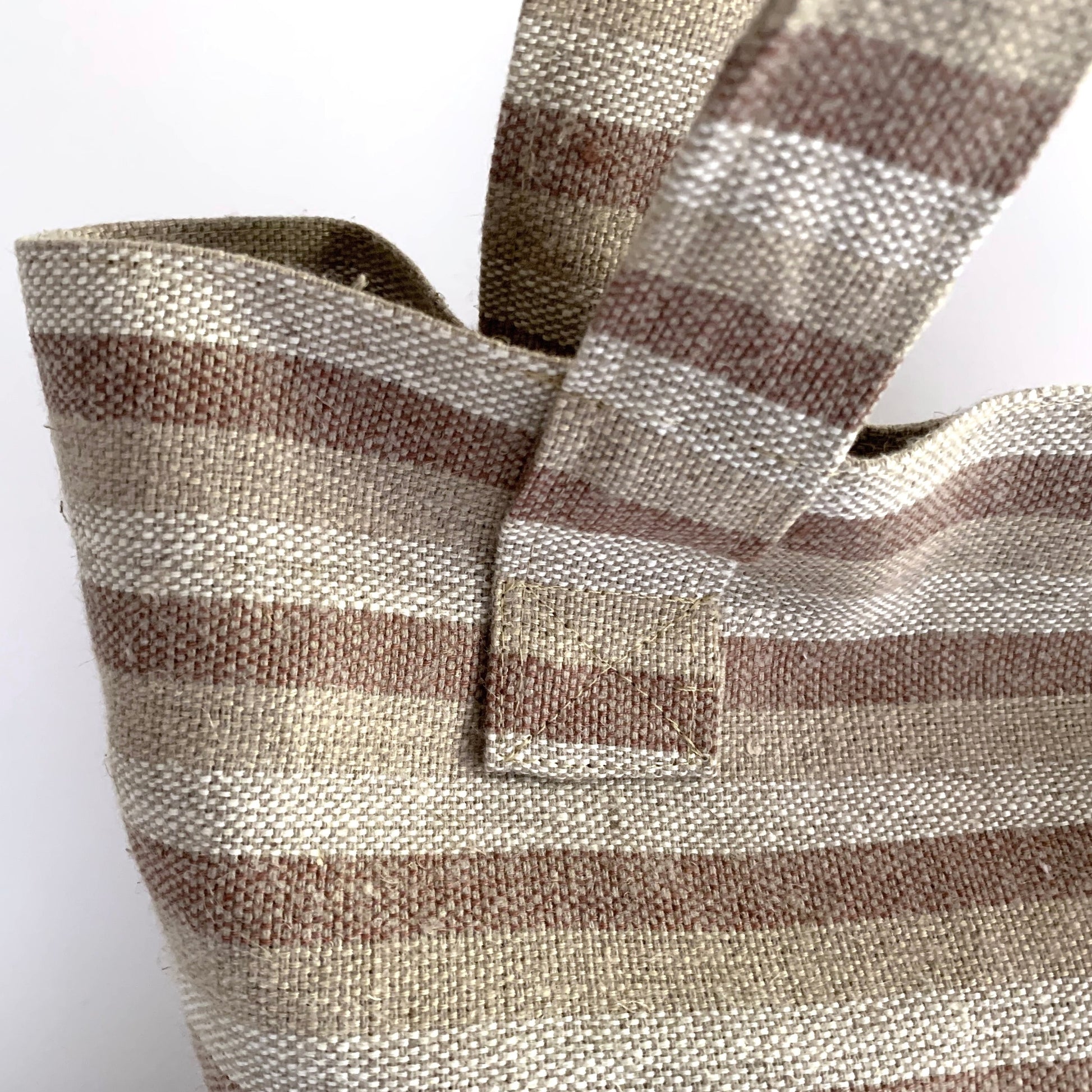 close up detail of woven striped fabric in neutral colors on beach bag