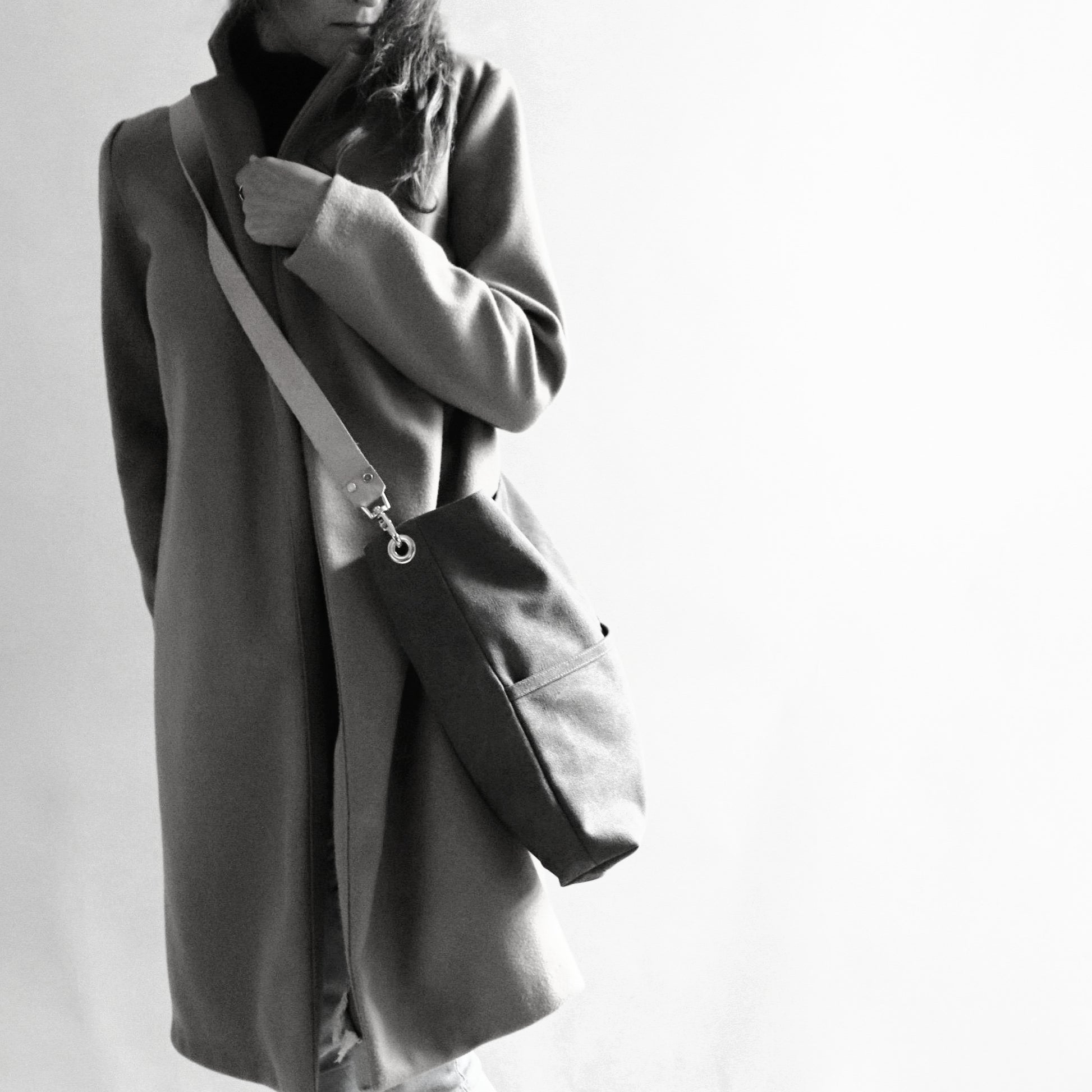Model in long coat holding oversized hobo bag crossbody style