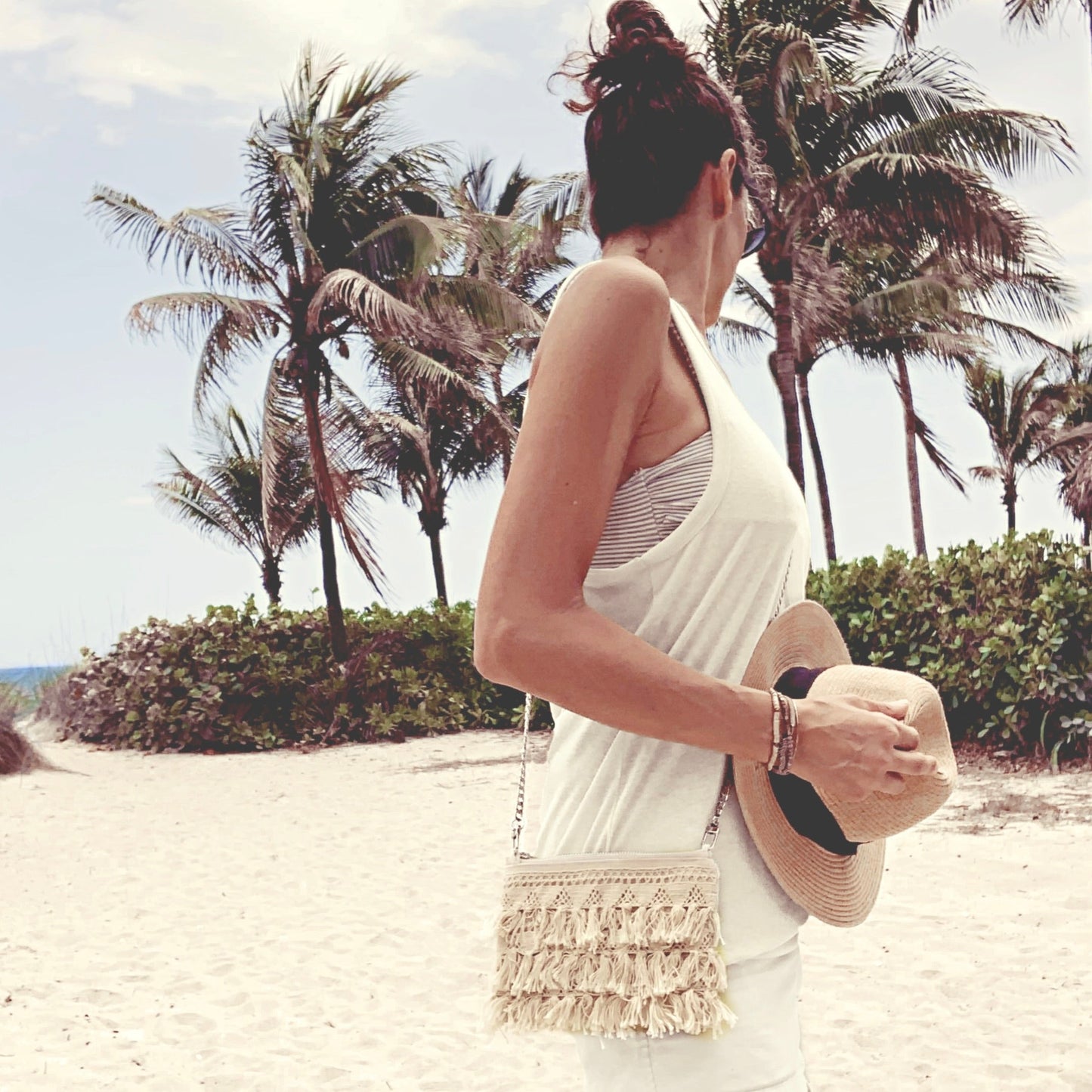 Lifestyle photo, crossbody purse with fringe trim tassel on tropical beach 