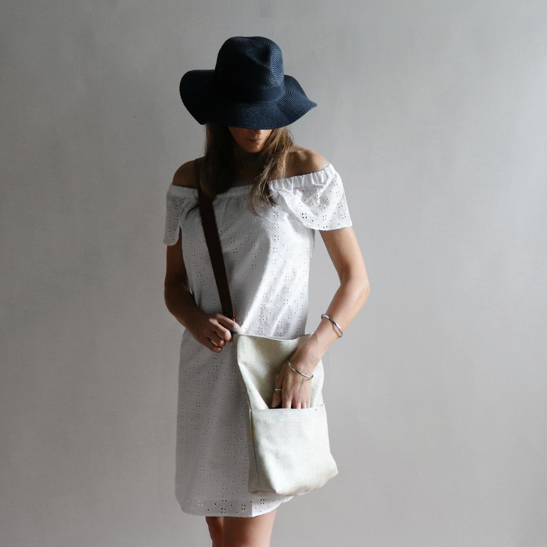 lifestyle photo of model in white sundress with woven crossbody bag